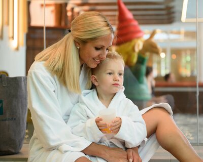 Mutter und Sohn im Bademantel beim Babybecken