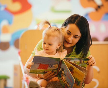 Betreuerin mit Baby beim Buchlesen