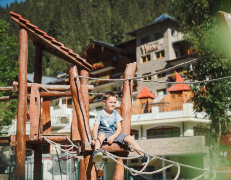 Junge sitzt auf Kletterturm