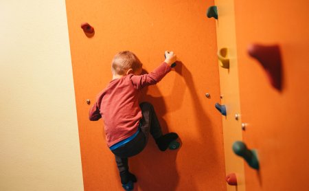 Junge beim Klettern auf der Kletterwand