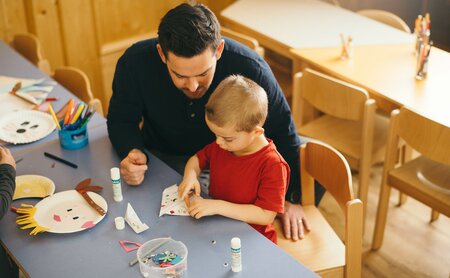 Kind beim Basteln mit Betreuer