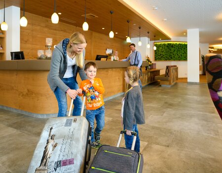 Familie beim Einchecken an der Rezeption