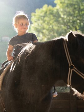 Mädchen sitzt auf Pony
