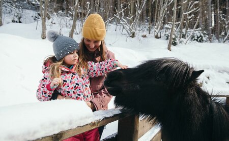 Kind streichelt Pony im Winter