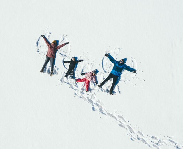 Drohnenbild von Familie beim Schneeengel machen